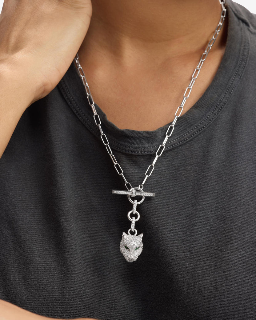 Person wearing a black shirt with a silver chain necklace featuring a wolf pendant.