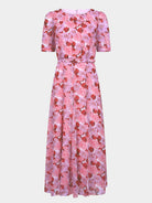 A pink floral midi dress with short puff sleeves, a round neckline, and a matching fabric tie belt at the waist, shown against a light gray background.