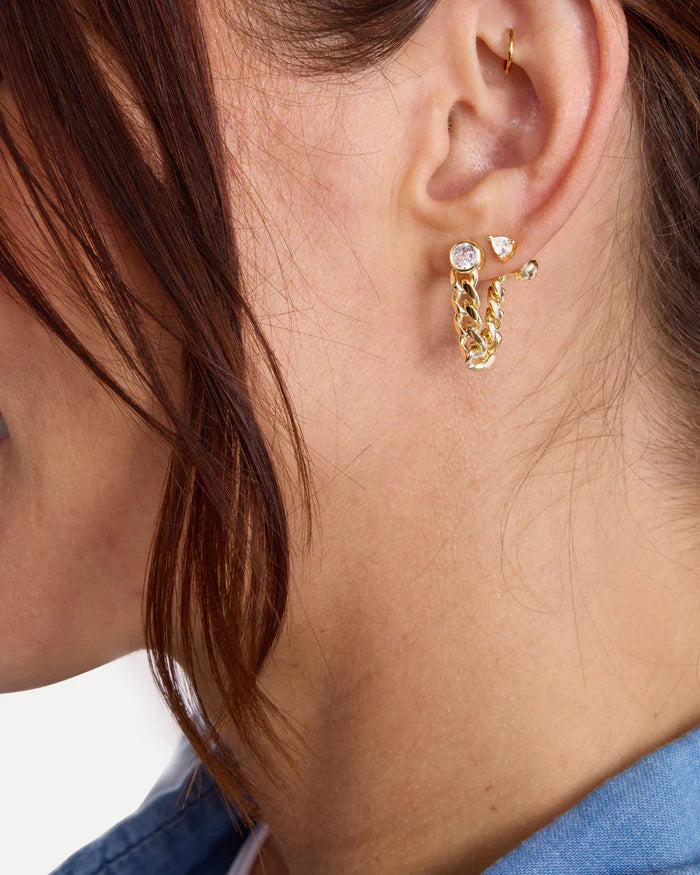 Close-up of an ear wearing gold hoop earrings with small gemstones.