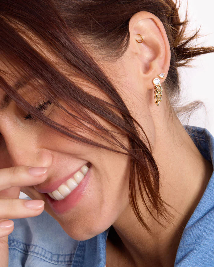 Close-up of a woman wearing gold hoop earrings with a blurred background