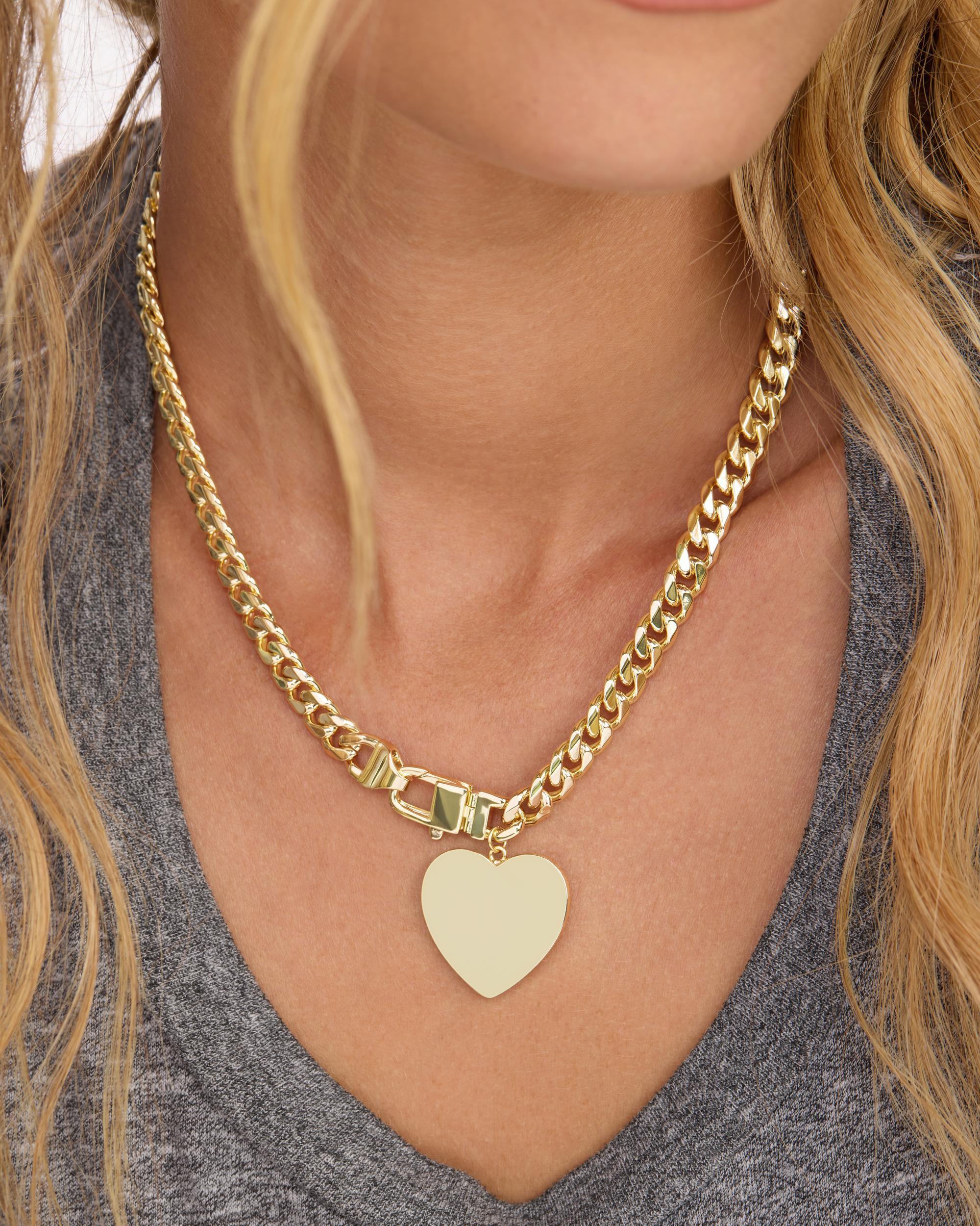 Gold chain necklace with a heart pendant worn by a person.