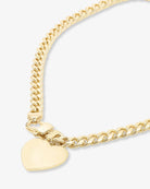 Gold chain bracelet with a heart-shaped tag on a light gray background
