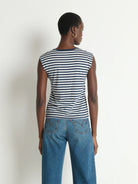 Person wearing a striped shirt and jeans against a plain background