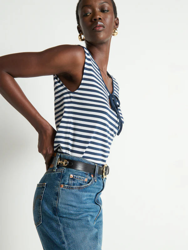 Woman wearing a striped tank top and blue jeans against a white background