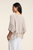 Woman wearing a beige knitted top with a plain background