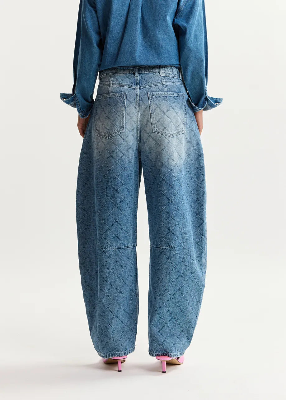 Person wearing blue jeans and a matching top on a white background