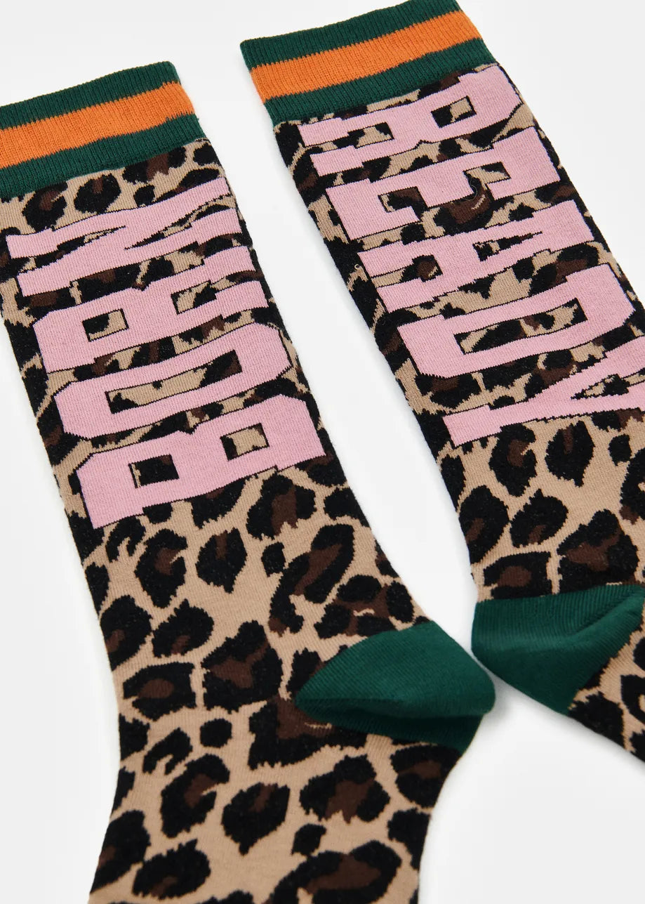 A pair of crew socks featuring a leopard print pattern, large pink 'BORN' text on one sock, and 'READY' on the other, with green and orange striped ribbed cuffs.
