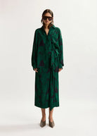 Woman wearing a green patterned outfit on a white background