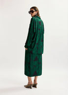Woman wearing a green patterned dress on a white background