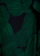 A close-up of a dark green and black tropical leaf pattern, likely a fabric swatch or garment detail.