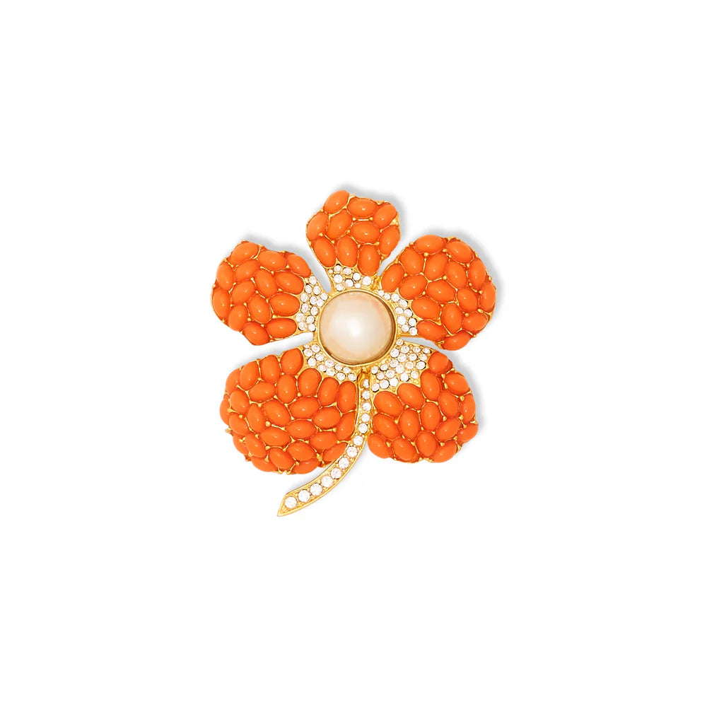 Orange flower-shaped brooch with a central pearl on a white background