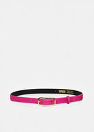 A vibrant magenta pink belt with a gold buckle, displayed horizontally on a light gray background. The inner lining is black with gold branding text.