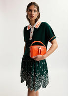 Woman holding an orange handbag against a white background