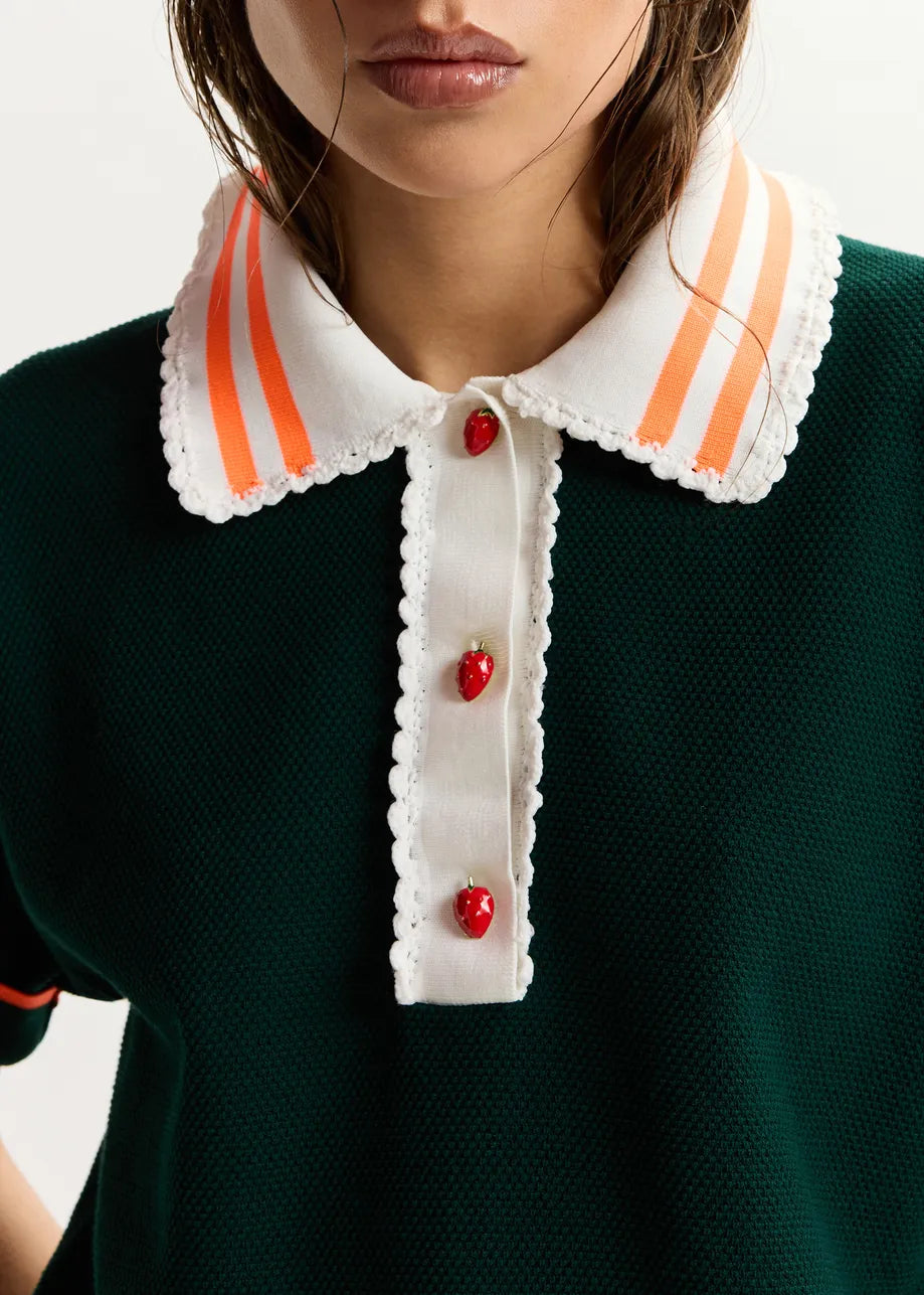 Close-up of a person wearing a green dress with a white collar featuring orange stripes and red buttons.