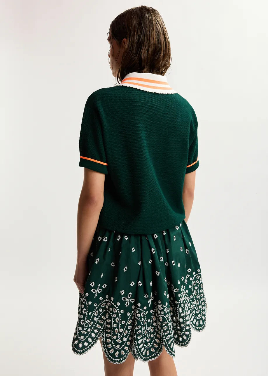 Person wearing a green dress with a patterned hem on a white background