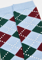 A close-up of a pair of argyle socks featuring a light blue base with dark green and burgundy red diamonds, decorated with rows of small white rhinestones.