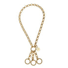 A gold-tone chain necklace with a central ring, a small round charm engraved with an 'N', and three dangling textured circular rings at the bottom, shown on a plain white background.