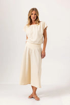 Woman wearing a cream-colored outfit on a white background