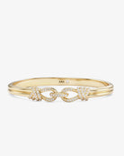 A gold bangle bracelet featuring a central chain-link motif embellished with pavé-set clear stones, shown on a light gray background. The inside of the band is stamped with 'MM'.
