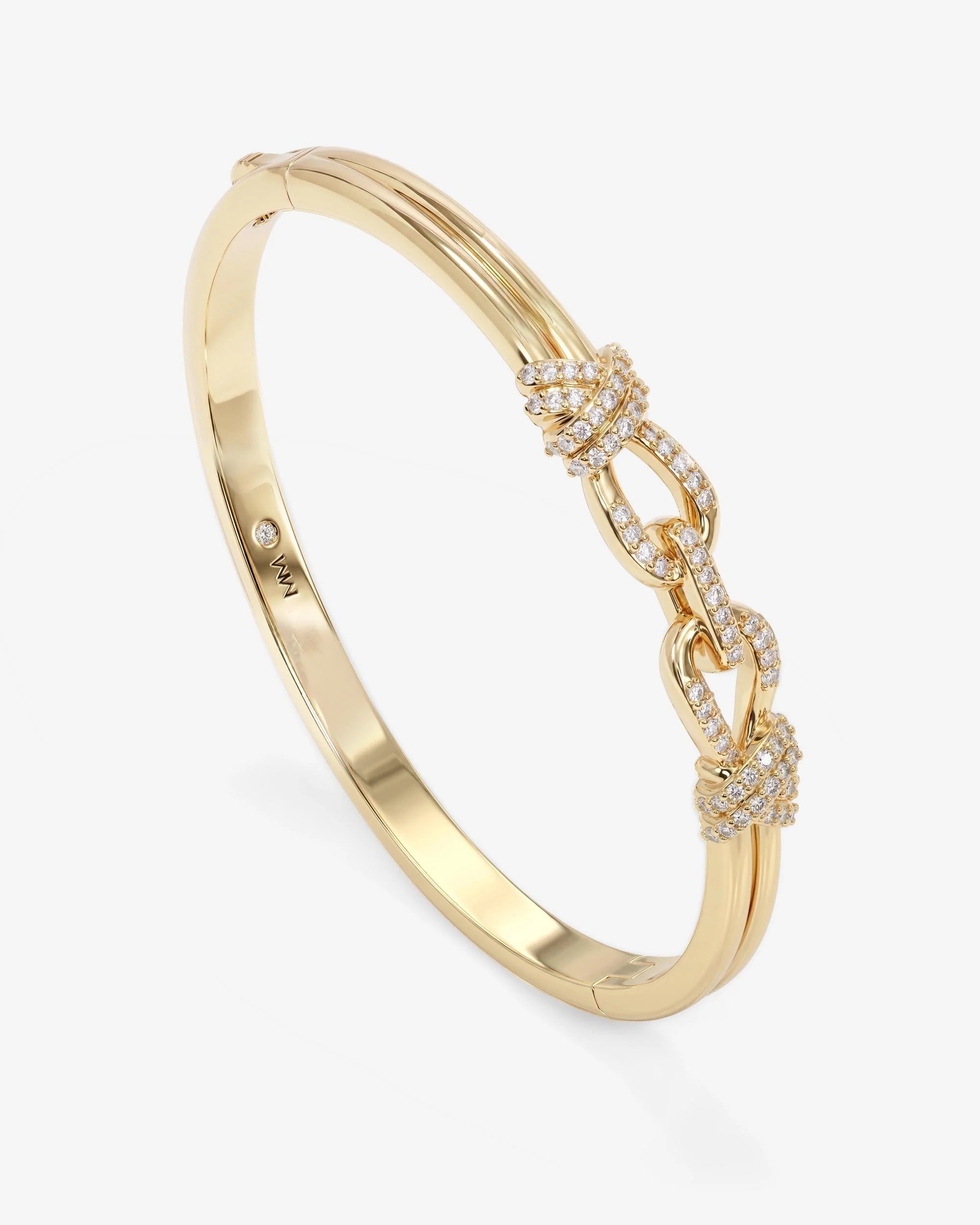 A gold bangle bracelet featuring three interlocking chain links embellished with pavé-set clear stones, shown on a light gray background.