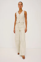 Woman wearing a cream vest and pants on a white background