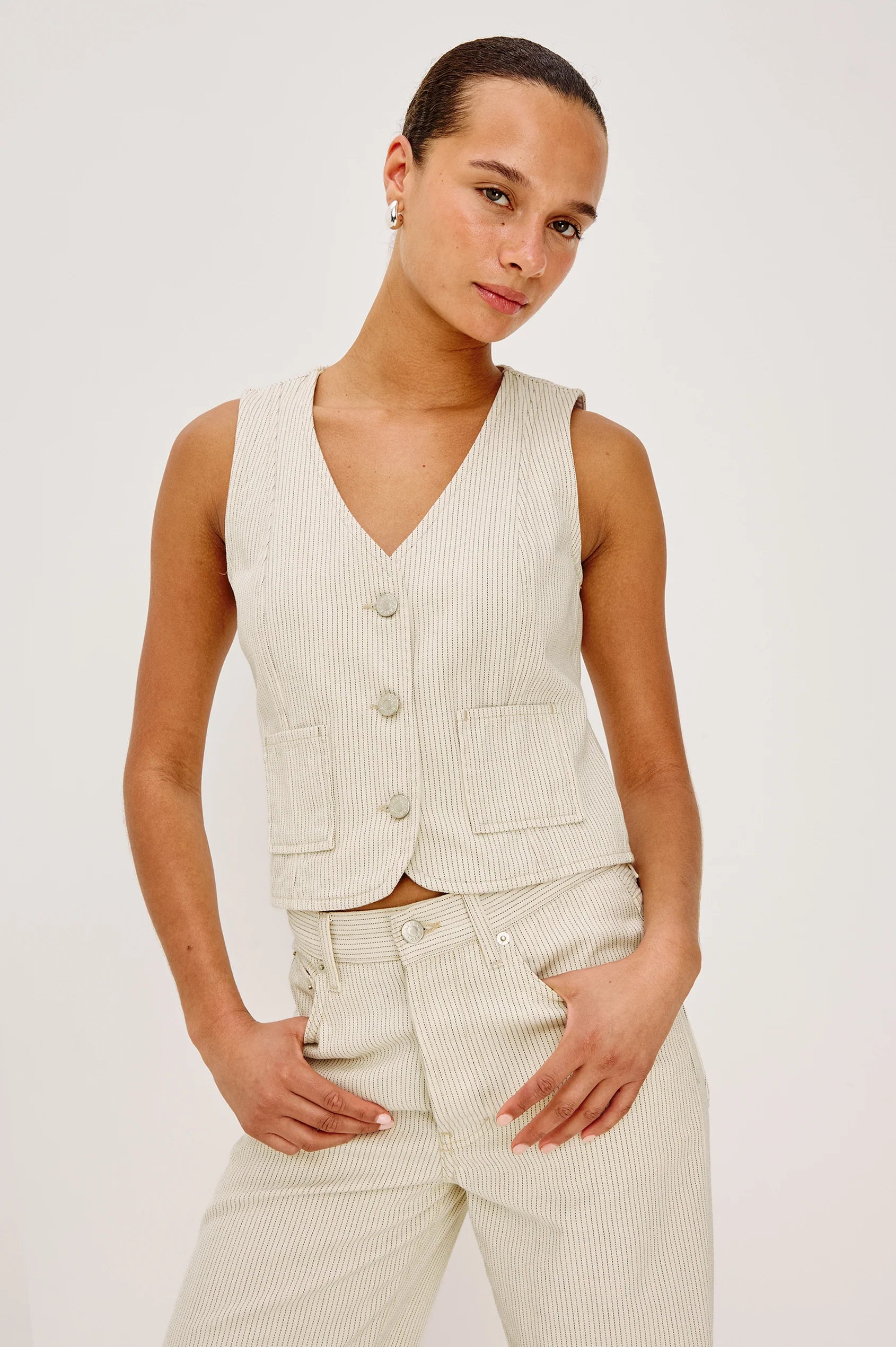 Woman wearing a beige vest and pants against a white background