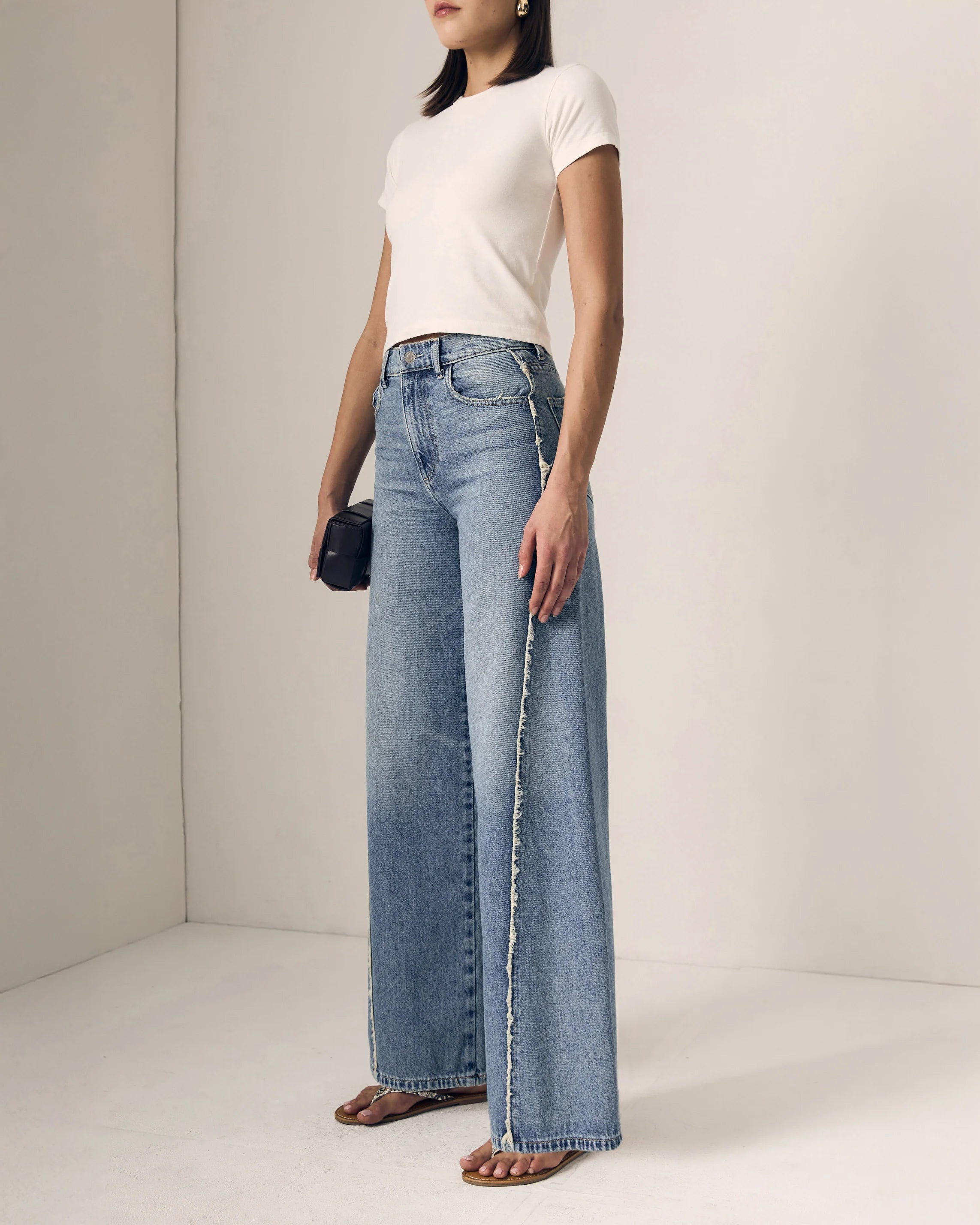 Person wearing a white t-shirt and blue jeans against a plain background