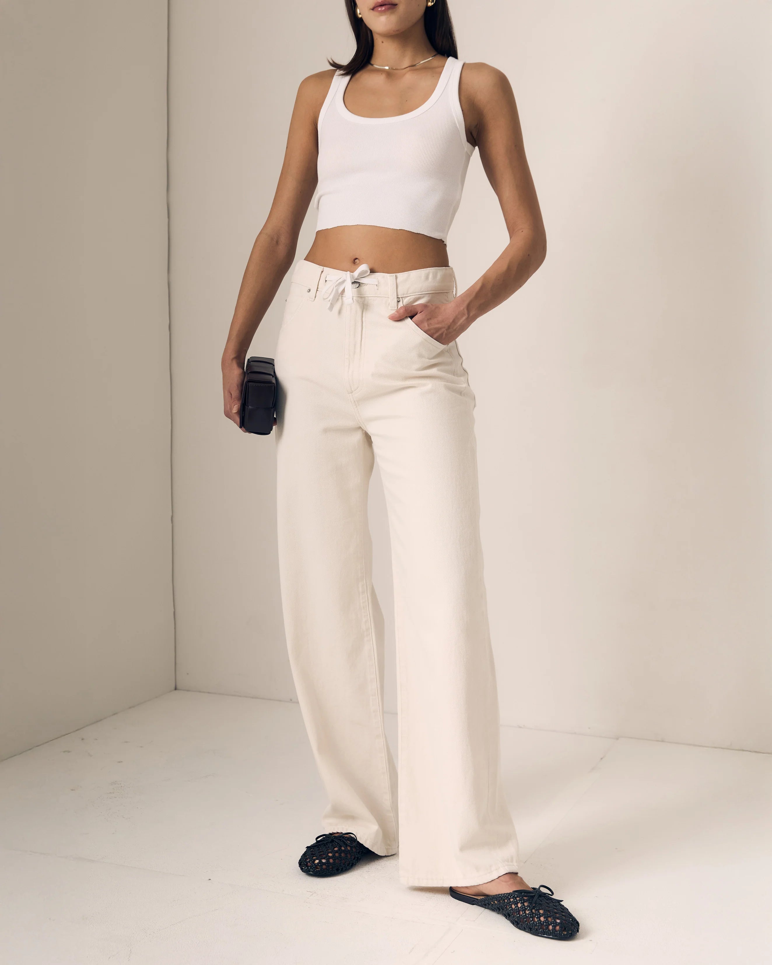 Person wearing a white crop top and beige pants against a plain background