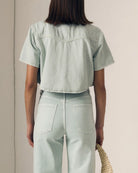Person wearing a light green denim outfit against a neutral background