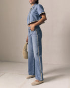 Person wearing a denim outfit with wide-leg jeans and a matching jacket against a neutral background.