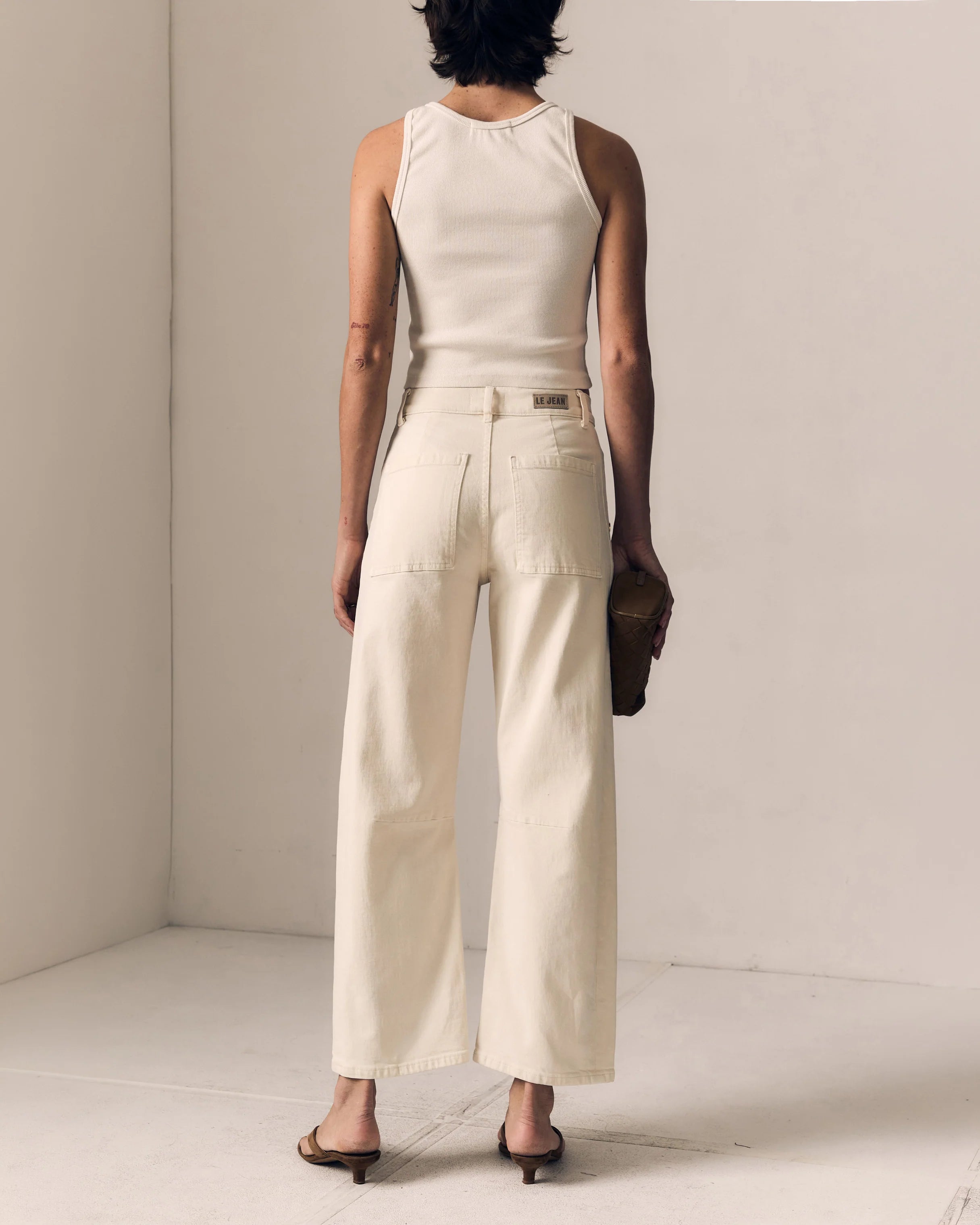 Person wearing a white sleeveless top and wide-leg pants against a plain background