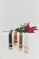 Set of belts with gold buckles on a white box with a pink flower.