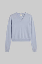 A light blue-gray V-neck knit sweater with long sleeves and ribbed cuffs and hem, displayed flat against a solid gray background.