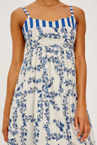 Woman wearing a blue and white striped dress with floral pattern on a white background