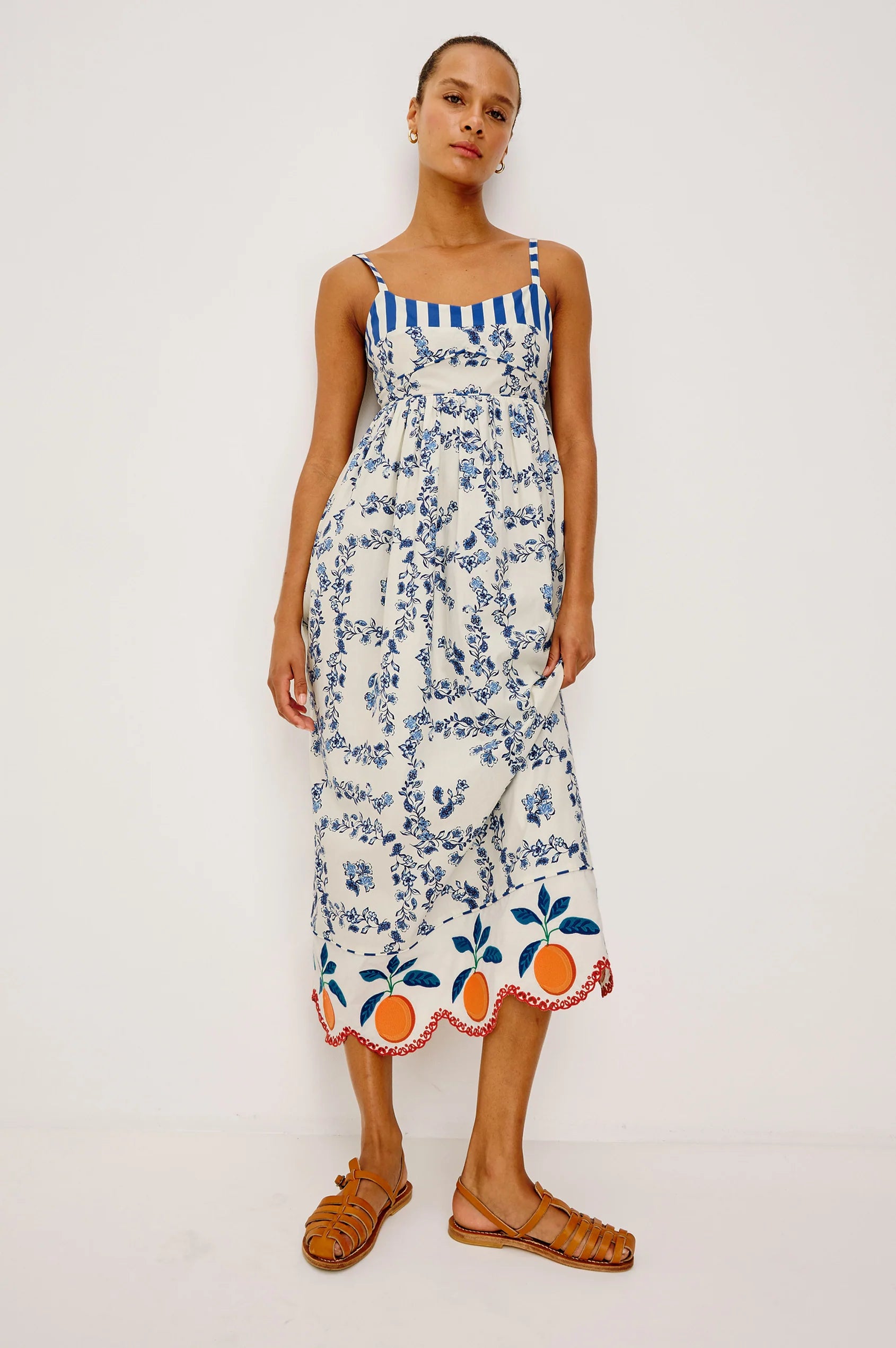 Woman wearing a floral dress with a blue and white striped top on a white background