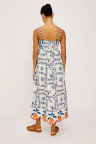 Woman wearing a floral dress with blue and orange details on a white background