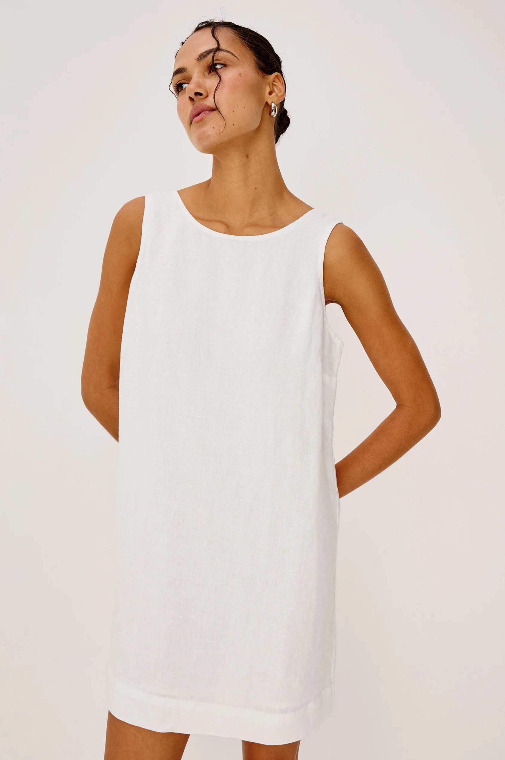 Woman wearing a white sleeveless dress against a plain background
