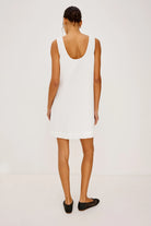Woman wearing a white sleeveless dress on a plain background
