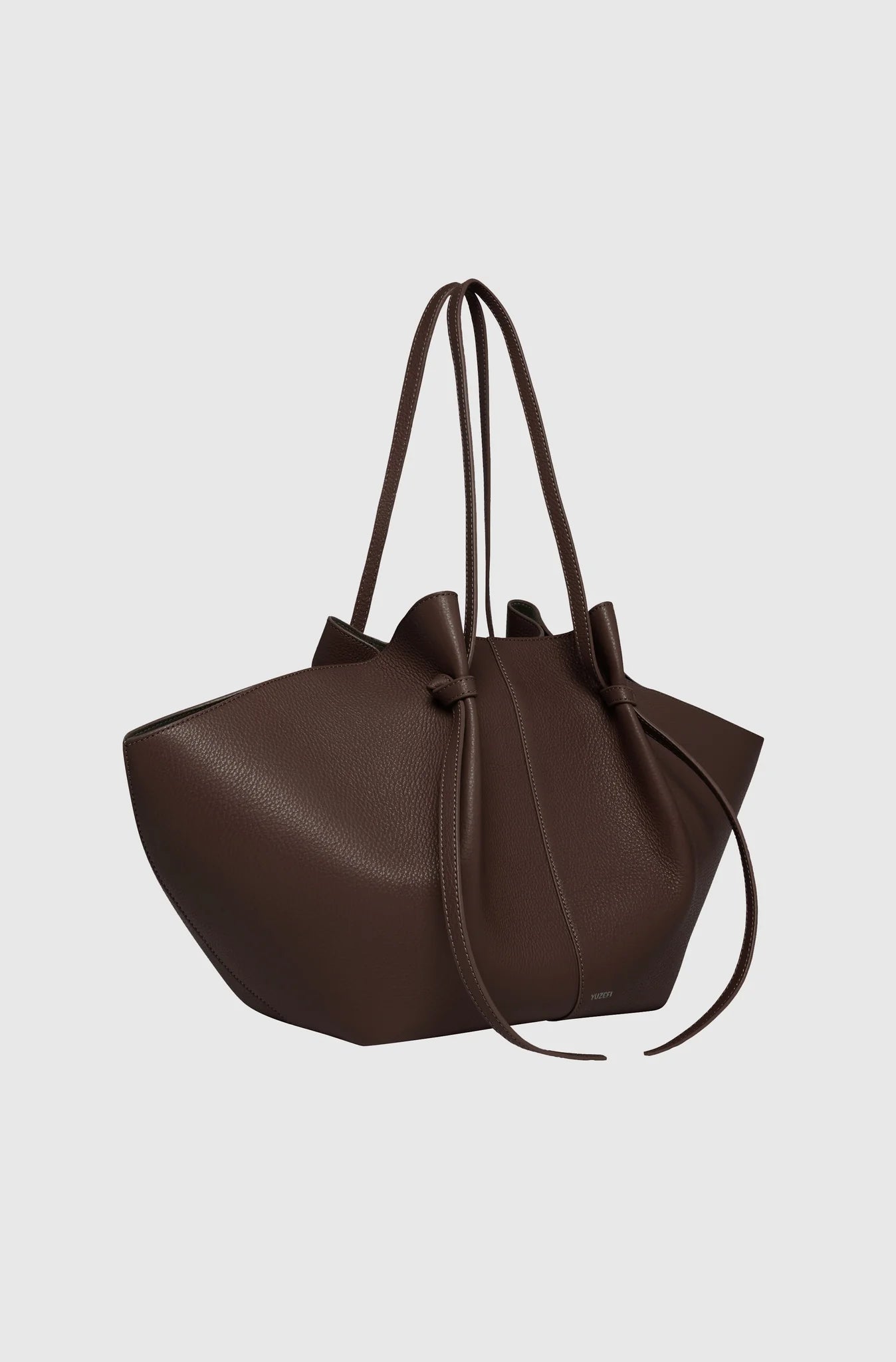 Brown leather handbag with drawstring on a light gray background