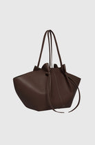 Brown leather handbag with drawstring on a light gray background