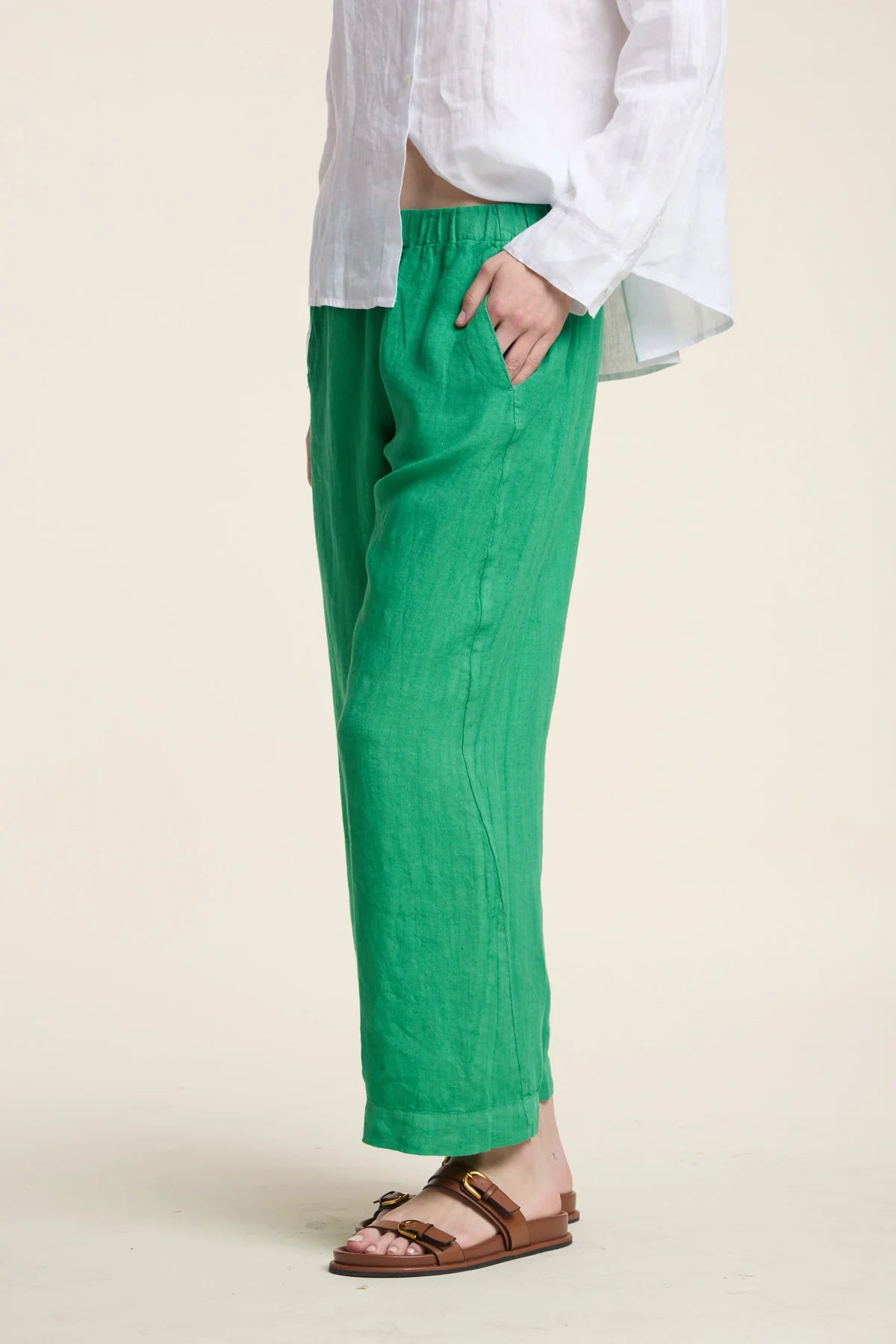 Person wearing green pants and a white shirt on a beige background