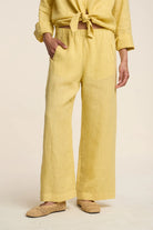 Person wearing a yellow outfit with wide-leg pants on a beige background