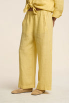 Person wearing yellow pants and a matching top on a beige background