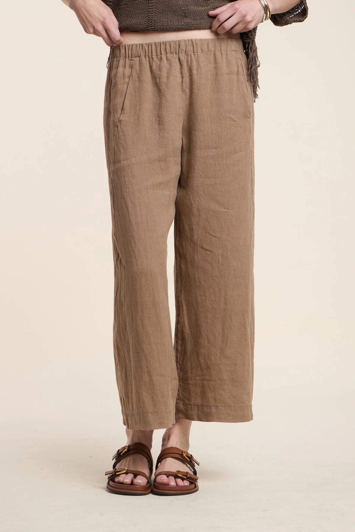 Person wearing brown wide-leg pants on a beige background