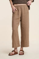 Person wearing brown linen pants on a beige background