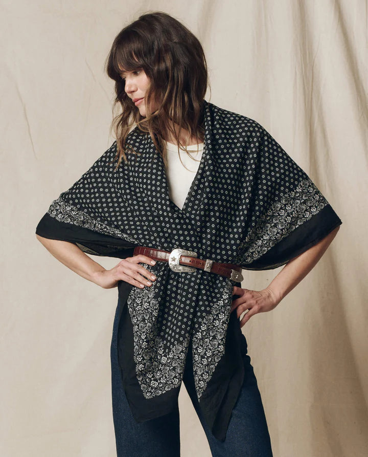 Woman wearing a black patterned scarf over her shoulders against a beige background