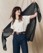 Woman holding a black patterned scarf against a beige background