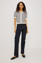 Woman wearing a black and white striped shirt and dark jeans on a white background