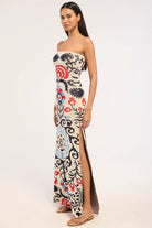 Woman wearing a strapless floral dress with a slit on a white background