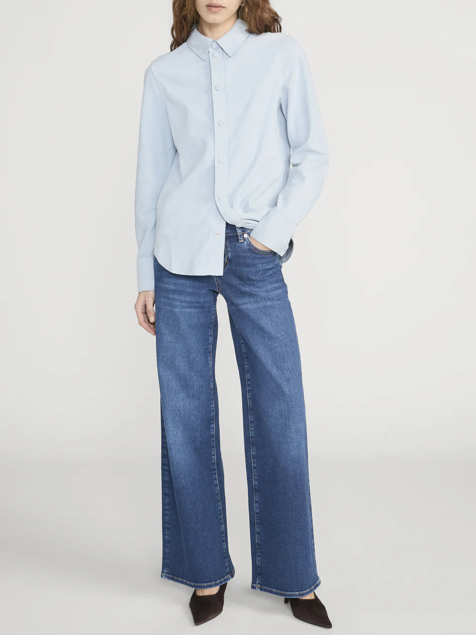 Person wearing a light blue shirt and blue jeans on a white background